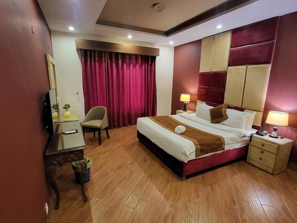 a hotel room with a bed and a desk and chair at Grand Millennium Hotel in Lahore