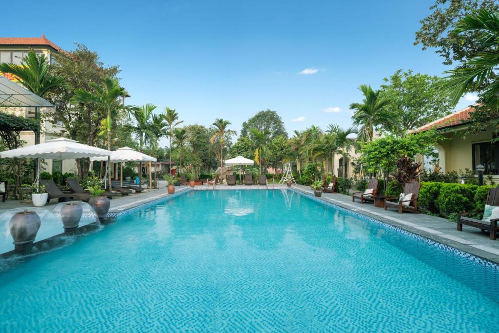 uma piscina num resort com cadeiras e guarda-sóis em Dong Ne Tam Coc Hotel & Resort em Ninh Binh