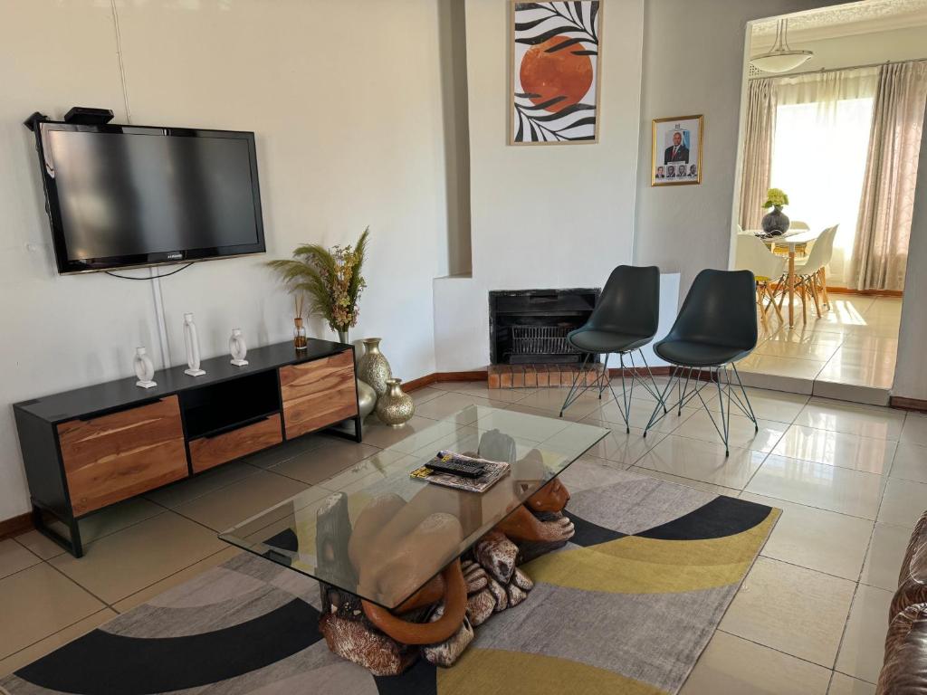 a living room with a tv and a table and chairs at Hi-Life Villa in Gaborone