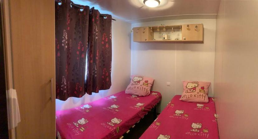 2 camas en una habitación pequeña con sábanas rosas en Camping les Goélands Bassin d'Arcachon 3 chambres Luxe, en Arès