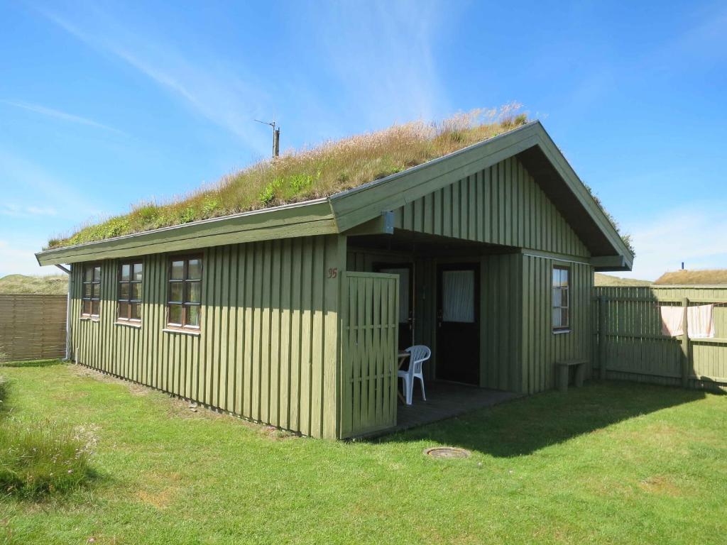 a green building with a grass roof with a chair at Scenic Holiday Home In Skagen, in Skagen