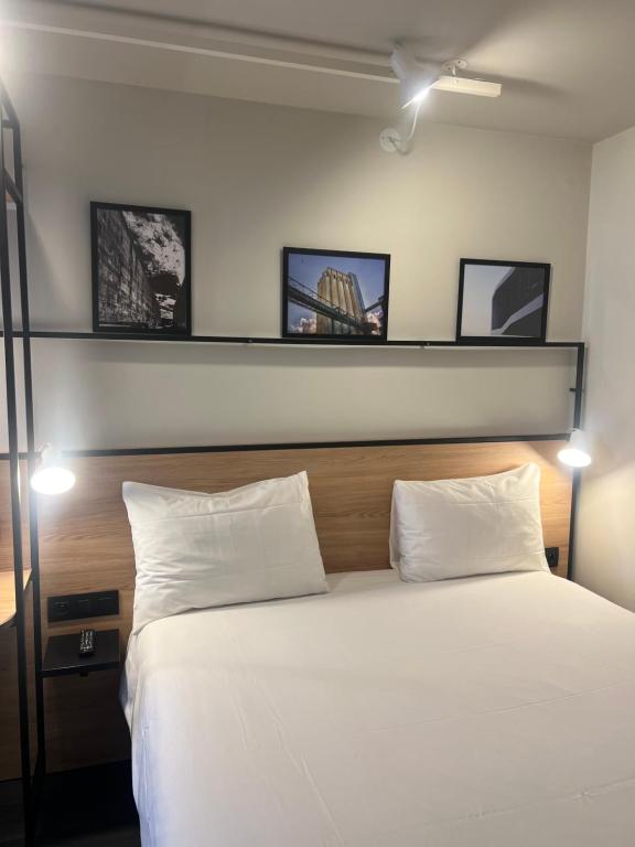 ein Schlafzimmer mit einem weißen Bett mit drei Bildern an der Wand in der Unterkunft ibis Lorient Centre Gare in Lorient