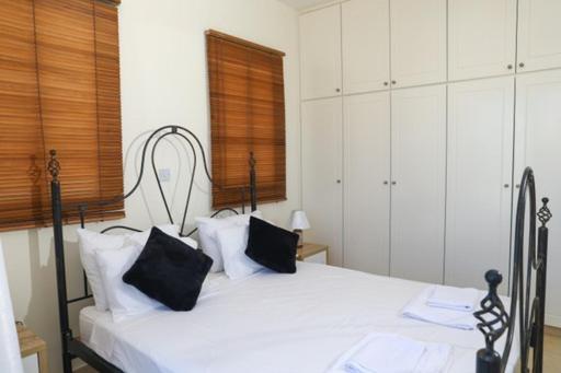 una camera da letto con un letto bianco con cuscini neri di Sunset Green 01 a Paphos
