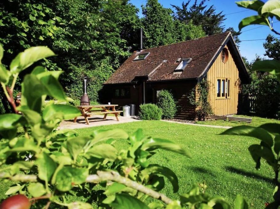a small house with a picnic table in the yard at The Potting Shed Sopley in Christchurch