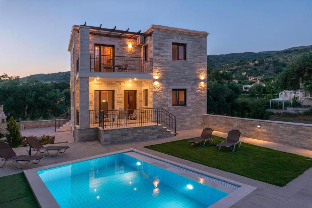 a villa with a swimming pool in front of a house at Tesoro luxury apartments in Sivota