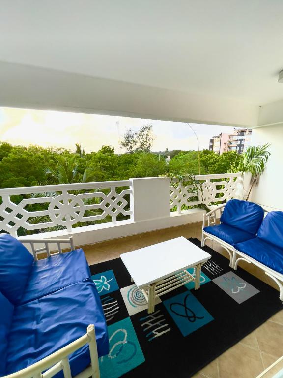 a balcony with blue chairs and a white table at Sunrise Resort 1BR Apartment in Nyali