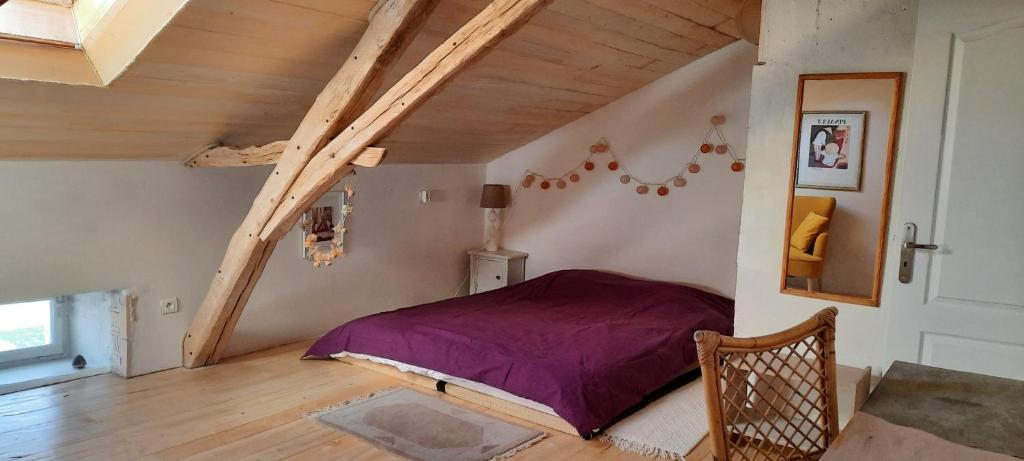 a bedroom with a purple bed in a attic at Loin de l&#39;agitation, dans le calme de la nature 