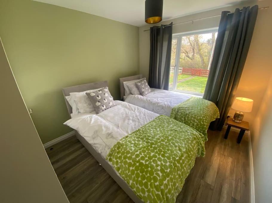 two beds with green and white comforters in a bedroom at Tummel View Pitlochry in Pitlochry