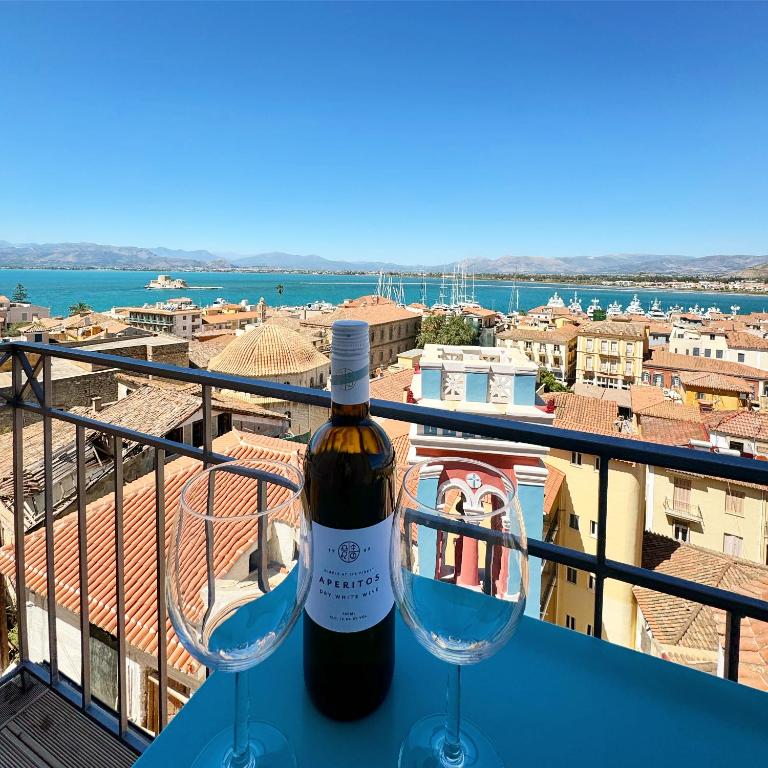 a bottle of wine and two wine glasses on a balcony at S&F Luxury Apartment in Nafplio