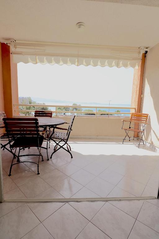 une salle à manger avec une table et des chaises et une grande fenêtre dans l'établissement T2 ARIA MARINA Route des Sanguinaires, Vue MER, Terrasse , Parking, Plage à 50M - 4pers, à Ajaccio