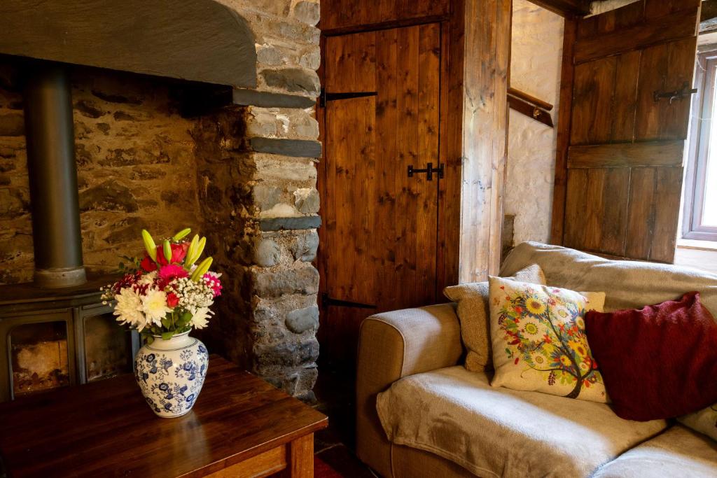 a living room with a couch and a vase of flowers on a table at Deer House in Machynlleth