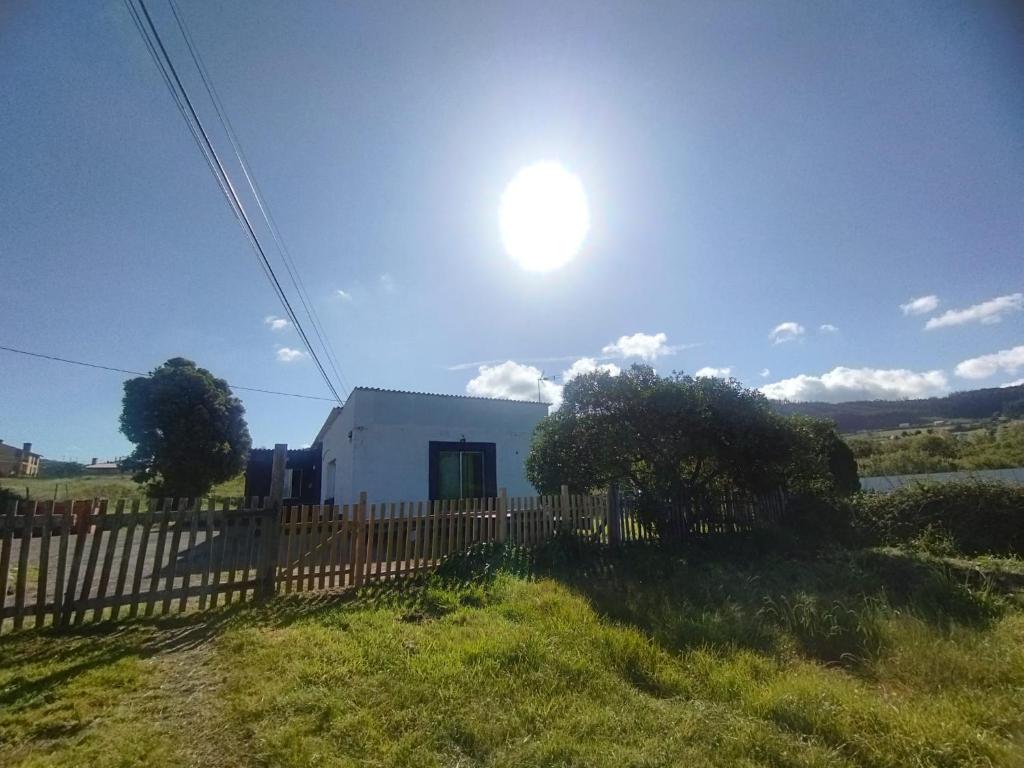Ein weißes Gebäude mit der Sonne hinter einem Zaun. in der Unterkunft Alojamiento PLAYA DE PANTIN in Valdoviño