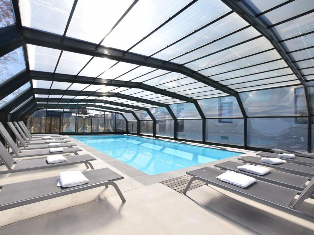 a swimming pool with lounge chairs and a large glass ceiling at Fancy Holiday Home in Sainte C cile with Pool House Indoor Pool in Sainte-Cécile
