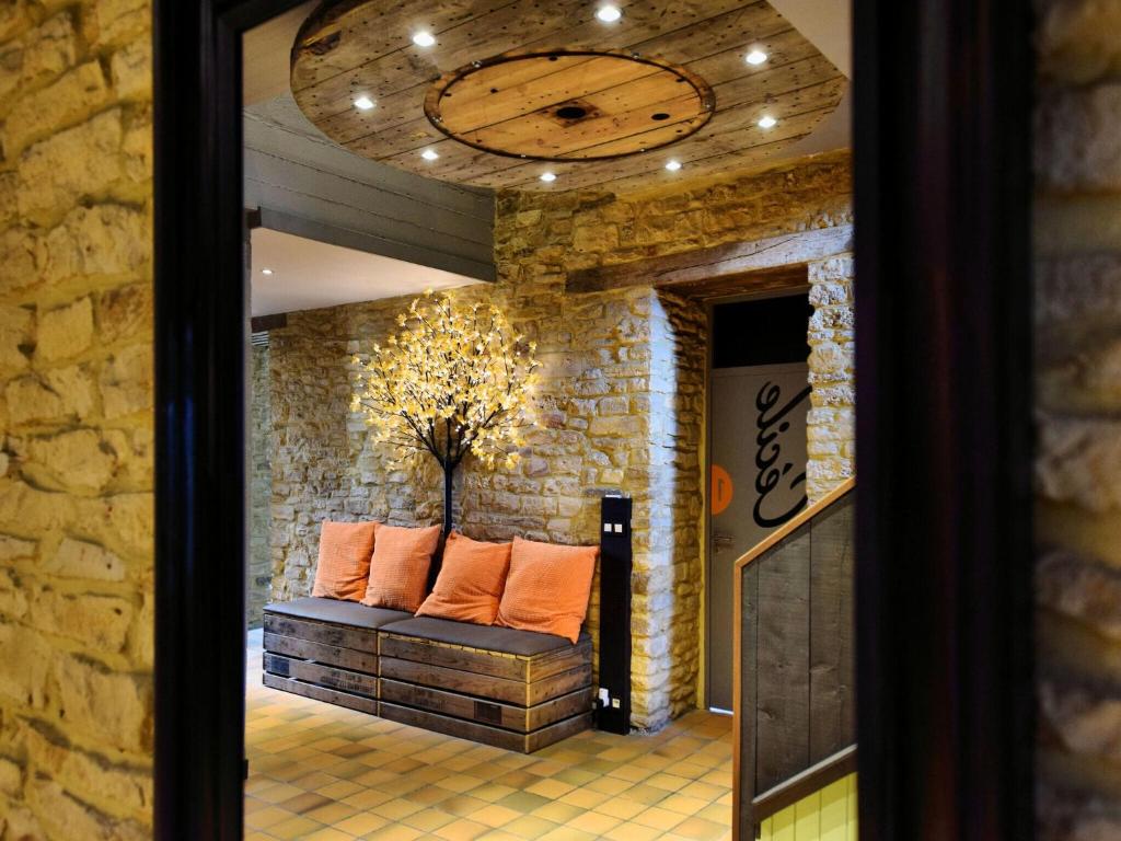 a room with a couch in a stone wall with a clock at Fancy Holiday Home in Sainte C cile with Pool House Indoor Pool in Sainte-Cécile