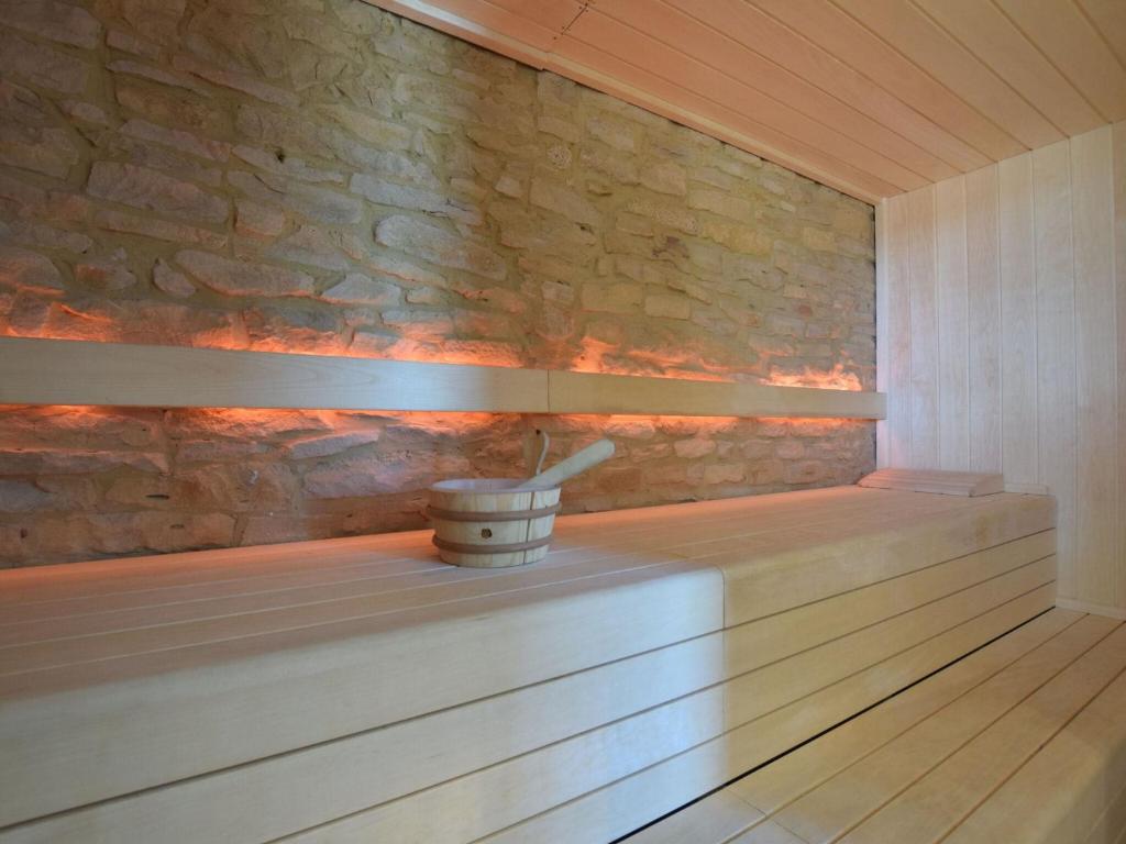 a sauna with a stone wall and a bucket at Fancy Holiday Home in Sainte C cile with Pool House Indoor Pool in Sainte-Cécile