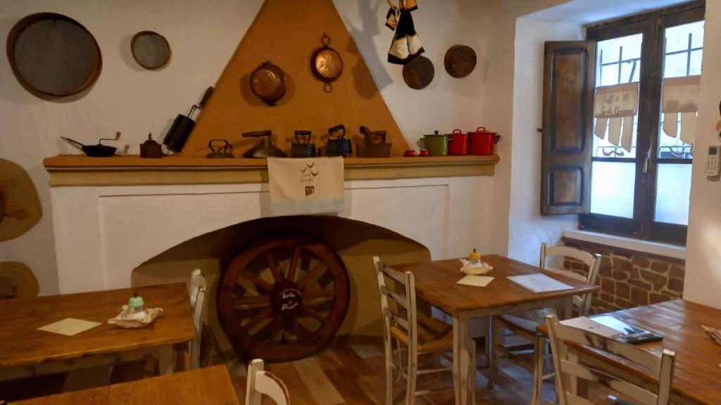 un restaurante con chimenea y 2 mesas y sillas en Un Tuffo nel passato "B&B Santu Giuvanni" en Fonni