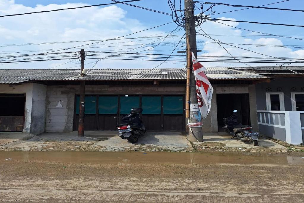 una moto parcheggiata di fronte a un edificio con una bandiera di SPOT ON 93908 Angel Guest House a Tangerang