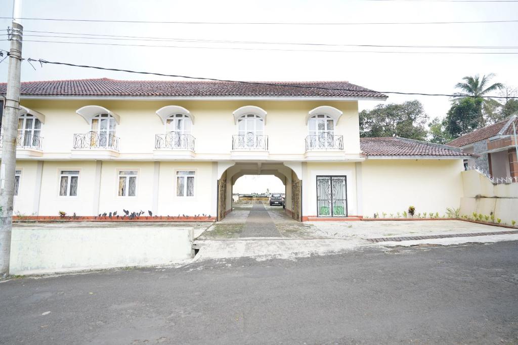 ein großes weißes Gebäude mit einem Torbogeneingang in der Unterkunft Capital O 93949 Hotel Popuci By Pupa Hospitality in Kuningan