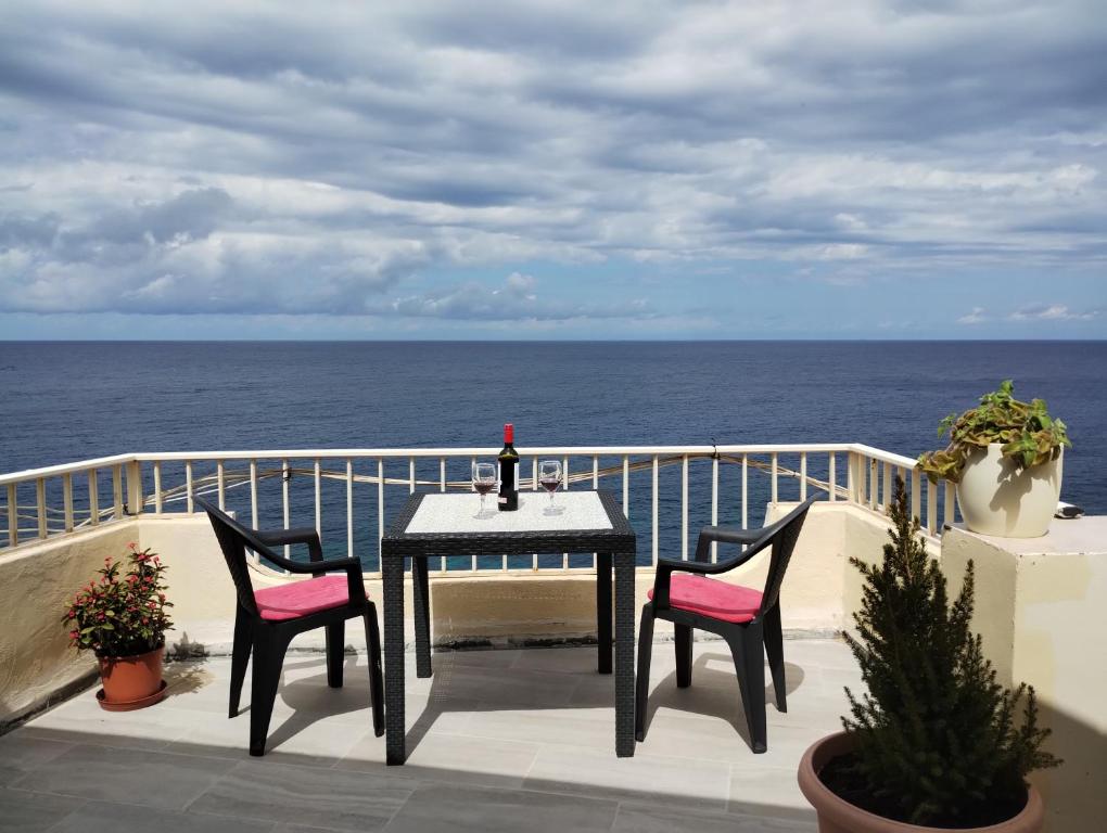 een tafel en 2 stoelen op een balkon met uitzicht op de oceaan bij Poseidons Seaview Penthouse in Marsalforn