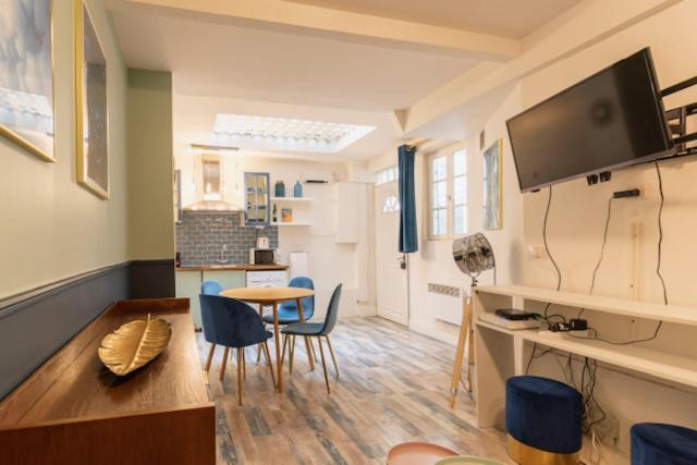 - un salon avec une table, des chaises et une télévision dans l'établissement Joli 2 pièces proche Marais, à Paris