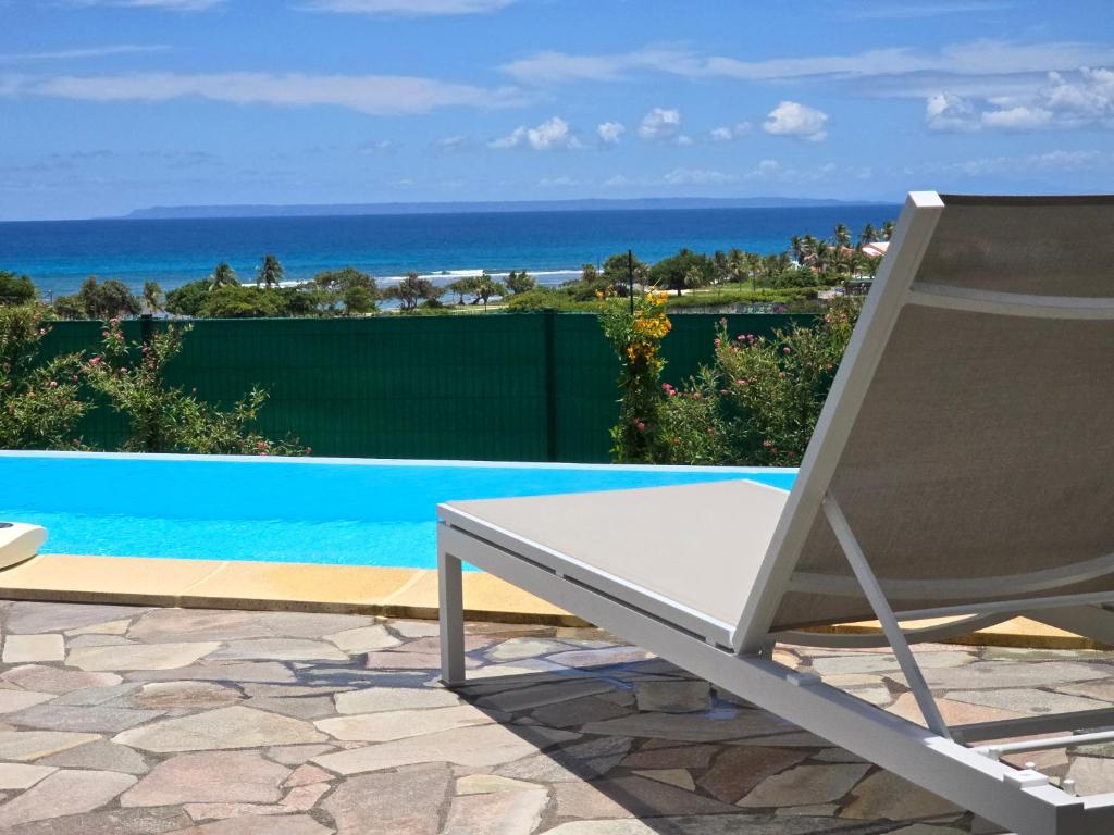 a white chair sitting next to a swimming pool at Villa piscine vue exceptionnelle mer et plage in Saint-François