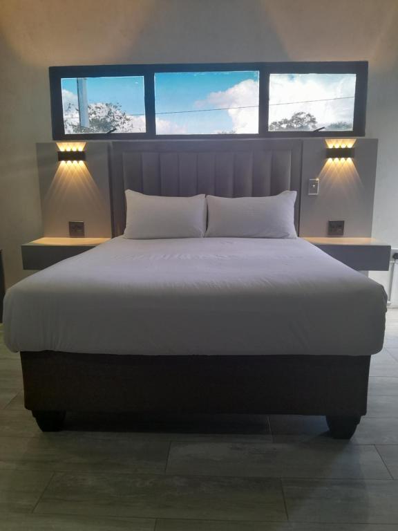 a bedroom with a large bed with two windows at PULA NALA LODGE in Rustenburg