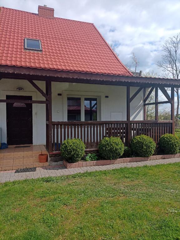 a house with a porch with a red roof at DOM w JESIONACH Brajniki - działka 1 HEKTAR in Jedwabno