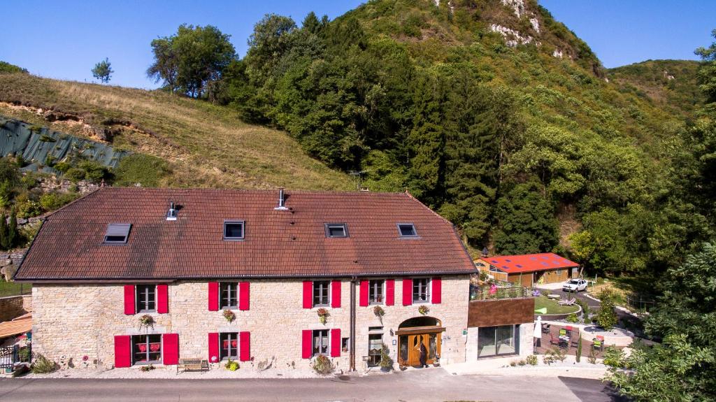 uma casa velha com persianas vermelhas e uma montanha em Domaine et chambres d'Hôtes des Fées em Pretin