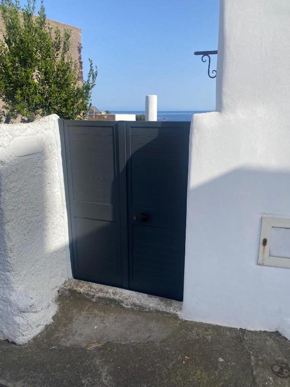 a black door in the side of a white wall at Casa Lilian in Stromboli