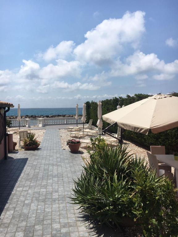 eine Terrasse mit einem Sonnenschirm, Pflanzen und dem Meer in der Unterkunft Casa Vacanze San Giacomo App Perla in Santo Stefano al Mare
