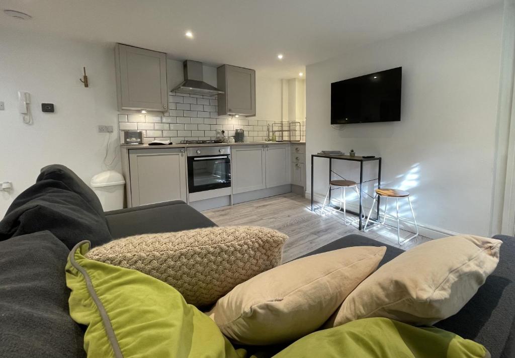 ein Wohnzimmer mit einem Sofa und einer Küche in der Unterkunft Apartment 1 St Georges in Cheltenham