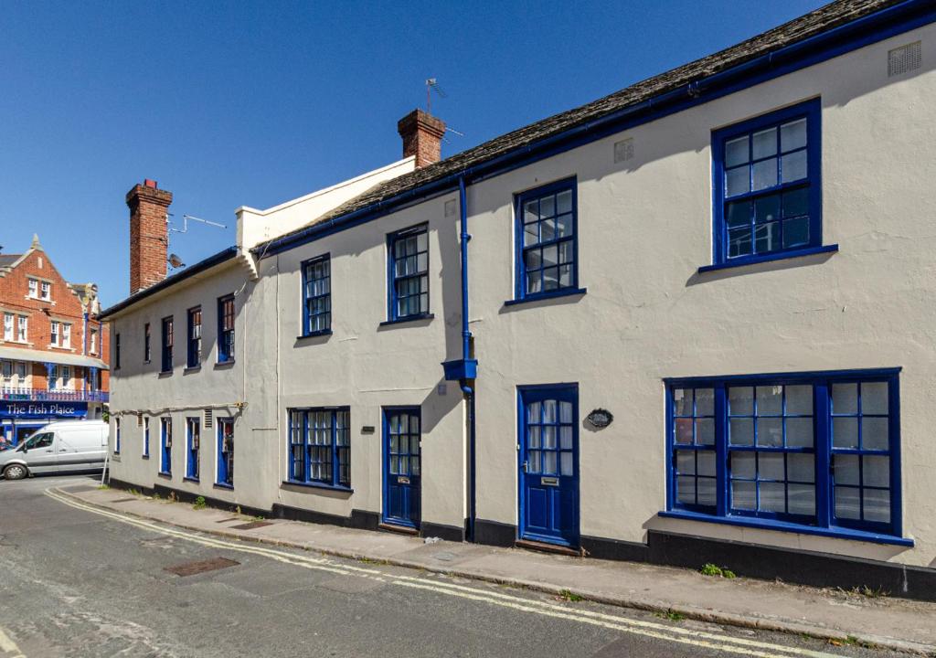 un edificio blanco con puertas y ventanas azules en una calle en Cutter Cottage, en Swanage