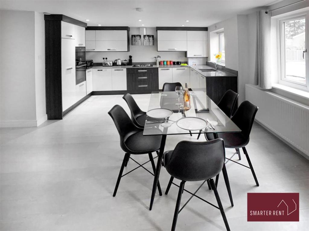 a kitchen with a table and black chairs in it at Bracknell -58c Harmanswater Road - 2 bedroom apartment in Bracknell