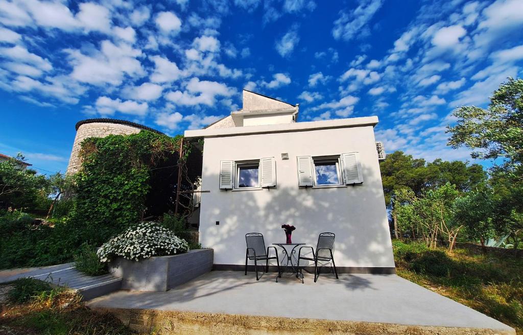 a white house with three chairs and a table at By the Mill in Rogoznica