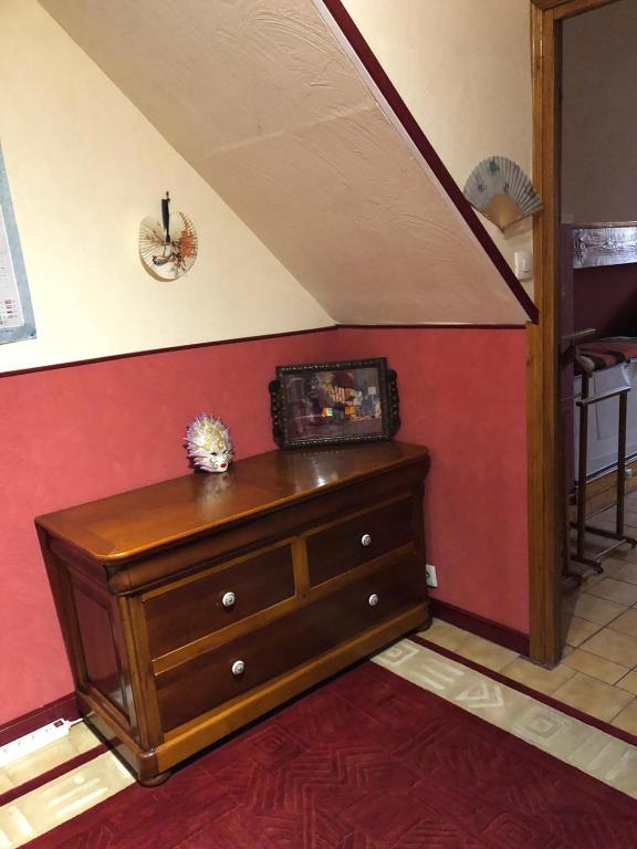 uma cómoda de madeira num quarto com uma parede vermelha em Yufan em La Ville-du-Bois