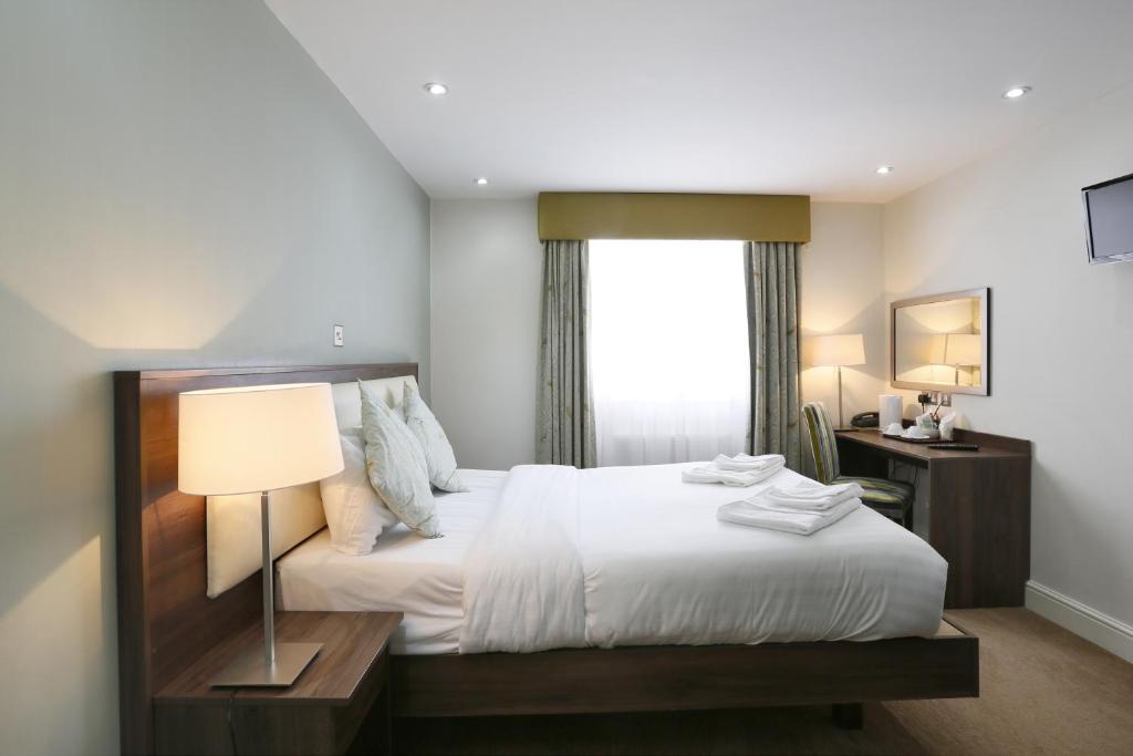 een slaapkamer met een bed met een lamp en een raam bij Hyde Park Boutique Hotel in Londen