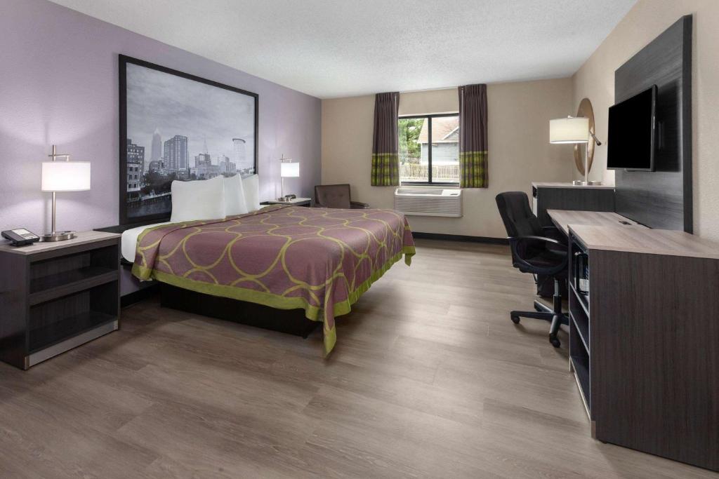 a hotel room with a bed and a desk at Super 8 by Wyndham Copley Akron in Copley