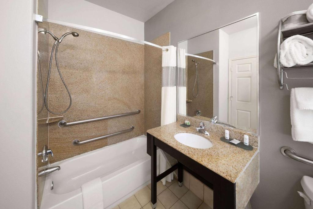 a bathroom with a sink and a tub and a shower at La Quinta by Wyndham Deer Park in Deer Park