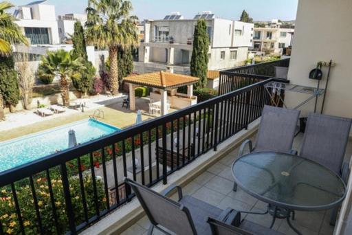 balcón con mesa y sillas y piscina en Sunset Green 03 en Pafos