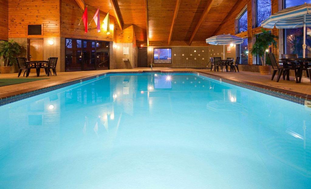 a large blue swimming pool with chairs and tables at AmericInn by Wyndham Manitowoc in Manitowoc