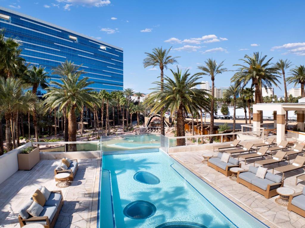 a swimming pool with chaise lounge chairs and palm trees at Virgin Hotels Las Vegas, Curio Collection by Hilton in Las Vegas