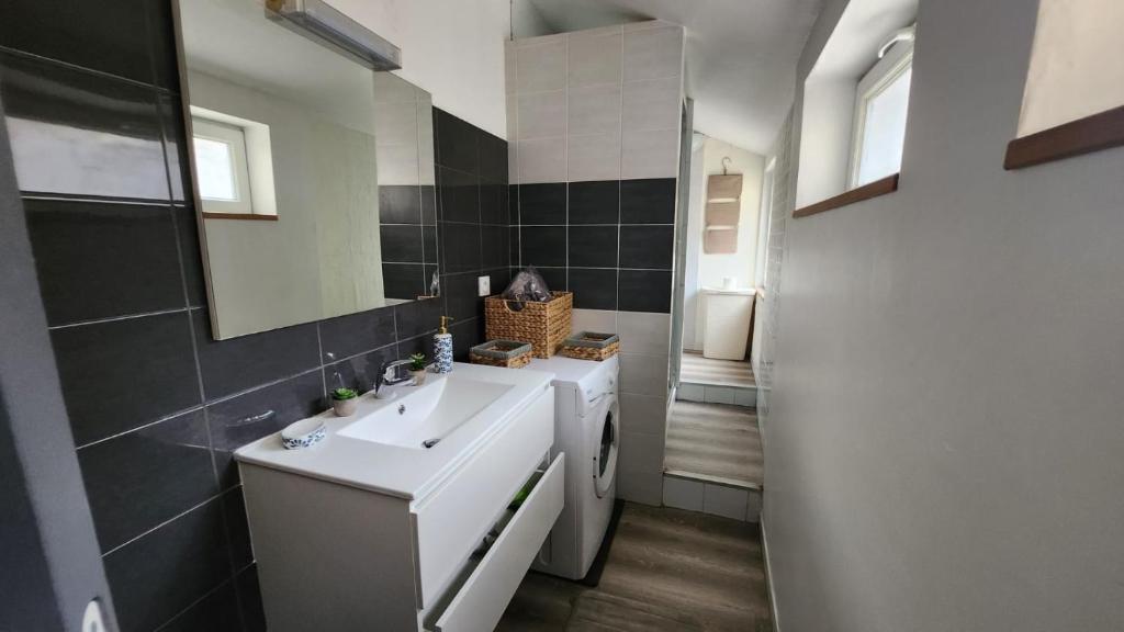 een badkamer met een witte wastafel en een spiegel bij Maison L'Atelier des Salines in Lons-le-Saunier