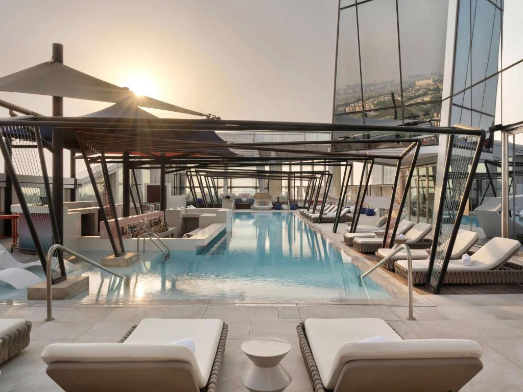 a pool on top of a building with lounge chairs at SO/ Uptown Dubai in Dubai