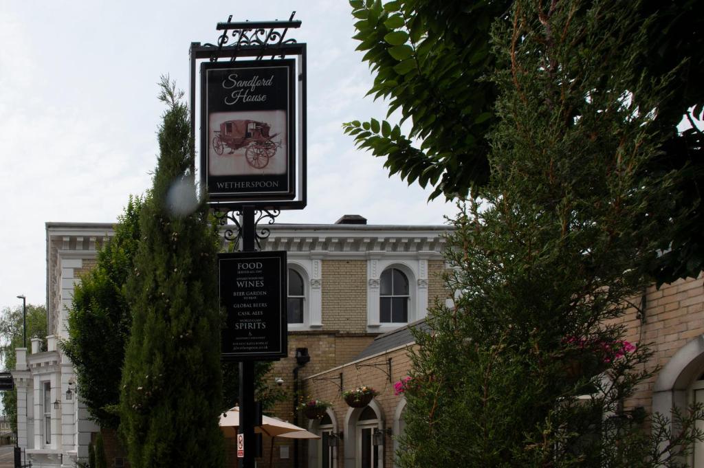 ein Schild an einer Stange vor einem Gebäude in der Unterkunft Sandford House Hotel Wetherspoon in Huntingdon