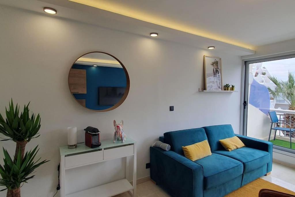 un salon avec un canapé bleu et un miroir dans l'établissement Studio de charme en centre-ville, à La Grande Motte