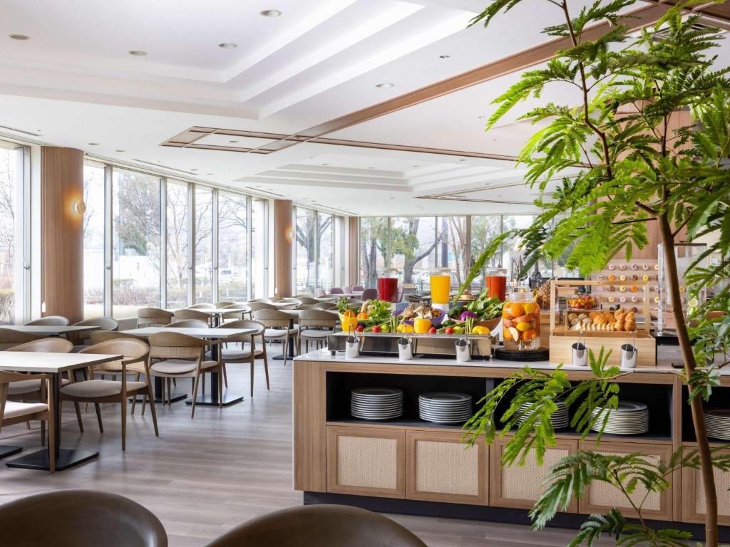 長野的住宿－Mercure Nagano Matsushiro Resort & Spa，用餐室设有桌椅和窗户。