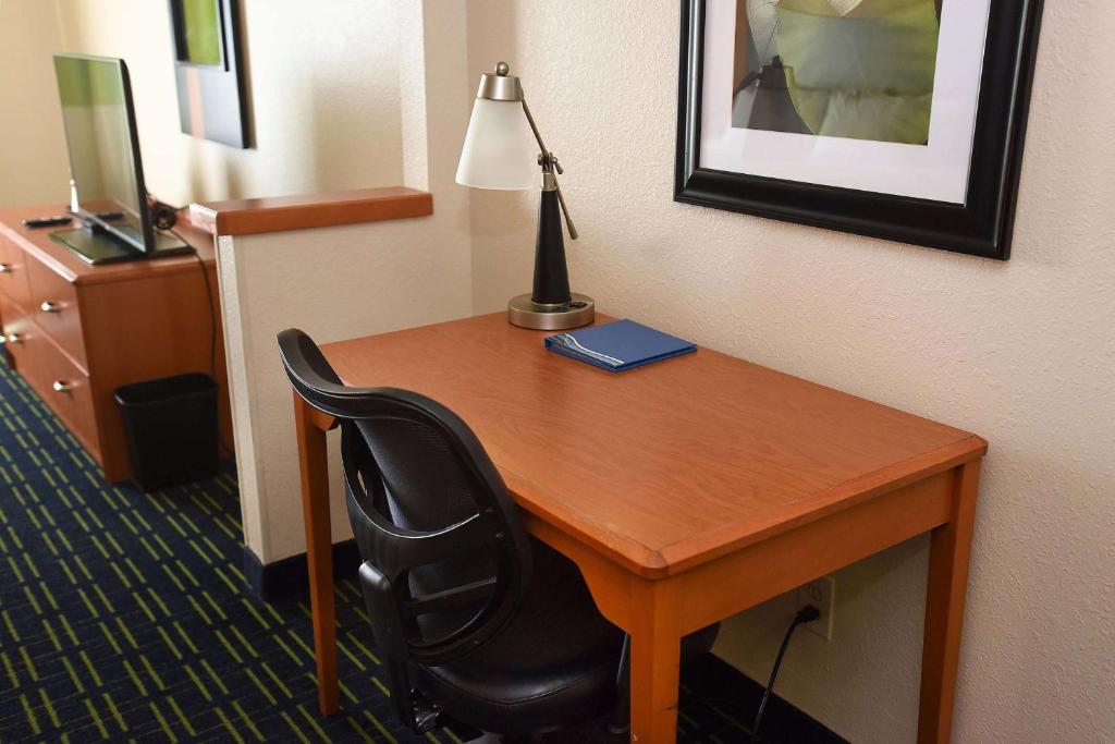 a desk in a hotel room with a lamp and a chair at AmericInn by Wyndham Topeka in Topeka