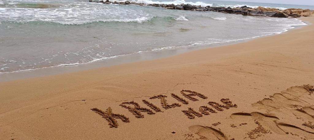 un cartel escrito en la arena de la playa en Krizia Mare, en Avola