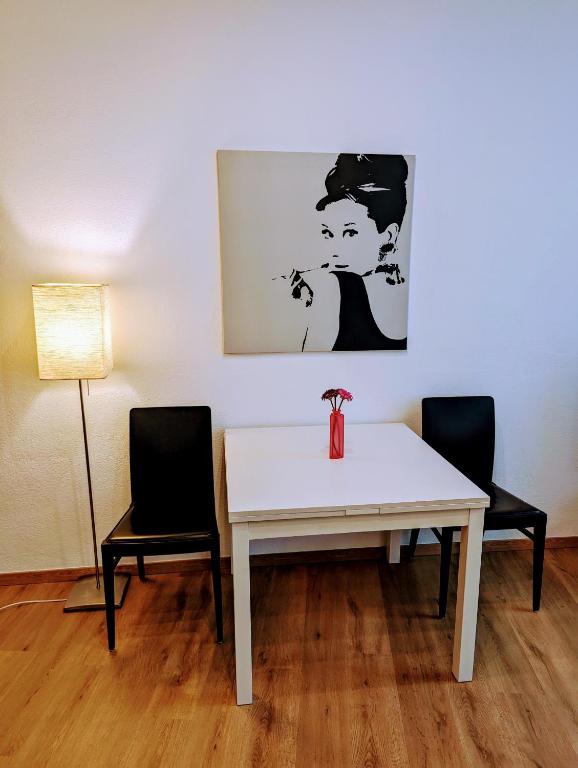 Biały stół z dwoma krzesłami i zdjęciem na ścianie w obiekcie Wohnung im Zentrum von Graz w Grazu