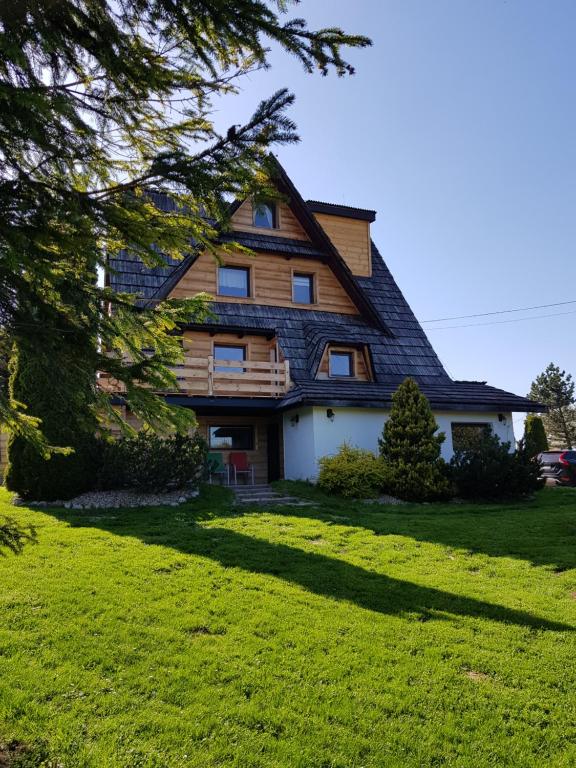 a house with a gambrel roof on a green lawn at Dom Górski Klimat-Willa 160 m2 z wewnętrzną sauną fińską, zniżki do Term Gorący Potok in Czerwienne